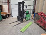 a green forklift in a warehouse with other equipment in the background