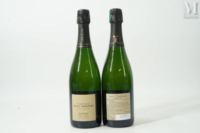 deux bouteilles de champagne posées l'une à côté de l'autre sur une surface blanche