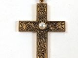 une image représentant une croix en or avec une perle au centre