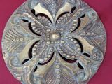 un objet métallique posé sur une surface rose, sur fond rouge