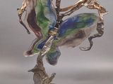 a figurine of a woman sitting on top of a tree branch