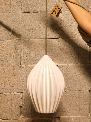 a woman that is standing next to a wall with a lamp