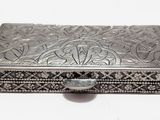 une vieille boîte en argent posée sur une surface blanche