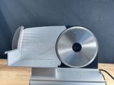 a close up of a meat slicer on a wooden table