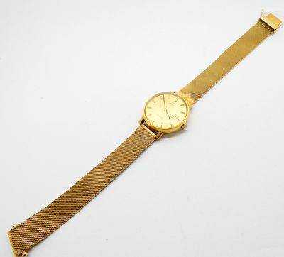 une montre en or posée sur une surface blanche