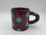 tasse à café à pois marron et bleus sur un fond blanc