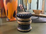 a black and gold vase sitting on a table next to other vases