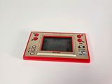 a small red and silver game console on a white surface