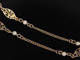 a close up of a gold chain with pearls on it