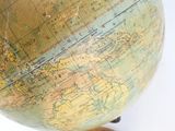 un petit globe posé sur un socle en bois, lui-même posé sur une surface blanche