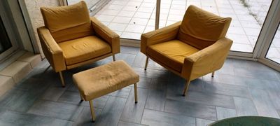 deux chaises et un pouf devant une porte vitrée