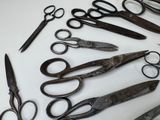 many pairs of scissors sitting on a white surface