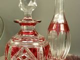 a glass bottle sitting on a table next to a glass vase