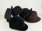 Plusieurs chapeaux sont alignés sur une surface blanche