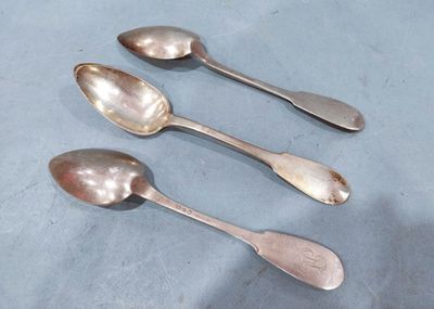 three silver spoons sitting on top of a table next to each other