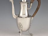 une cafetière ancienne en argent avec une poignée en bois sur un support