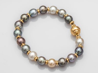 a close up of a bracelet with pearls on a white surface