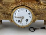 a gold clock sitting on a table next to a key