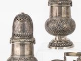 trois salières et poivrières en argent et un bol posé sur un socle