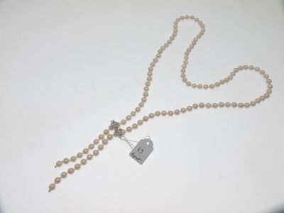 collier orné de perles blanches et d'une étiquette, posé sur un fond blanc