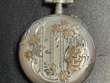 a silver pocket watch on a chain on a table