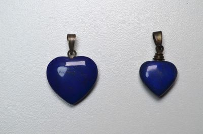 deux pendentifs bleus en forme de cœur sur fond blanc