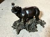 a statue of an elephant standing on a pile of leaves