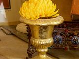 un vase en or contenant une fleur jaune, posé sur une table