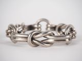 a close up of a silver bracelet on a white surface