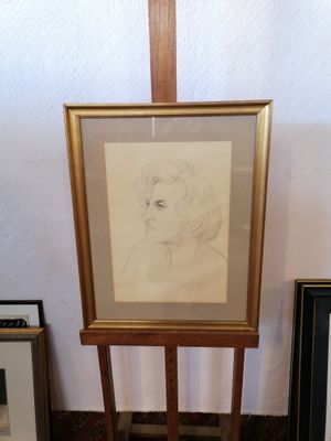 la photo d'un tableau représentant une femme, posé sur un chevalet