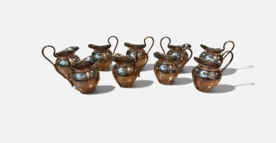 four small metal vases with handles and handles on a white surface