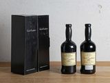 deux bouteilles de vin posées à côté d'une boîte noire sur une table en bois
