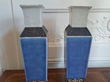 two blue vases sitting on a table in front of a white wall
