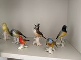 many birds that are sitting on top of a shelf