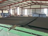 a green boat in a large warehouse with lots of windows