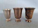 trois vases en argent posés les uns à côté des autres sur une table