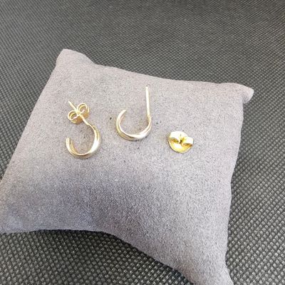 une paire de boucles d'oreilles en or posée sur un oreiller