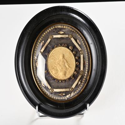 une pièce d'or dans un écrin noir posé sur une surface blanche