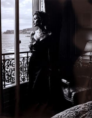 une photo en noir et blanc d'une femme assise devant une fenêtre