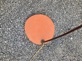 an orange disk on the ground next to a pair of scissors