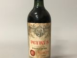 une vieille bouteille de vin rouge posée sur une table blanche