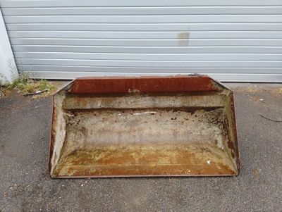 un seau en métal rouillé posé au milieu d'un parking