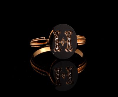 a close up of a gold ring with a diamond initial on it
