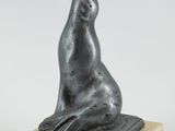 une statue représentant une chèvre assise sur un bloc de marbre