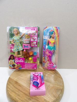 Deux poupées Barbie sont assises sur une planche à découper, à côté d'une boîte de brosses à dents