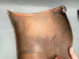 someone is holding a brown leather case with a pair of scissors next to it