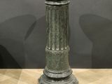 a green pedestal on a wooden floor with a black wall in the background