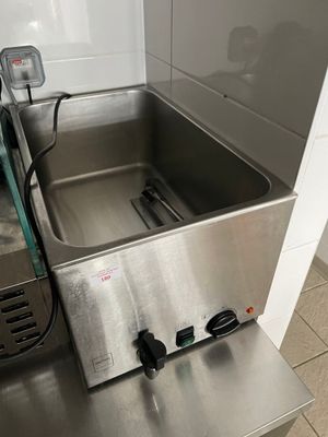 un évier en acier inoxydable dans une cuisine, à côté d'un four grille-pain