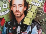 a man with long hair standing in front of a wall with cartoon characters