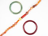 un collier de perles et une paire de bracelets posés sur une surface blanche